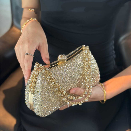 Gold crystal rhinestone evening clutch held by model wearing black dress